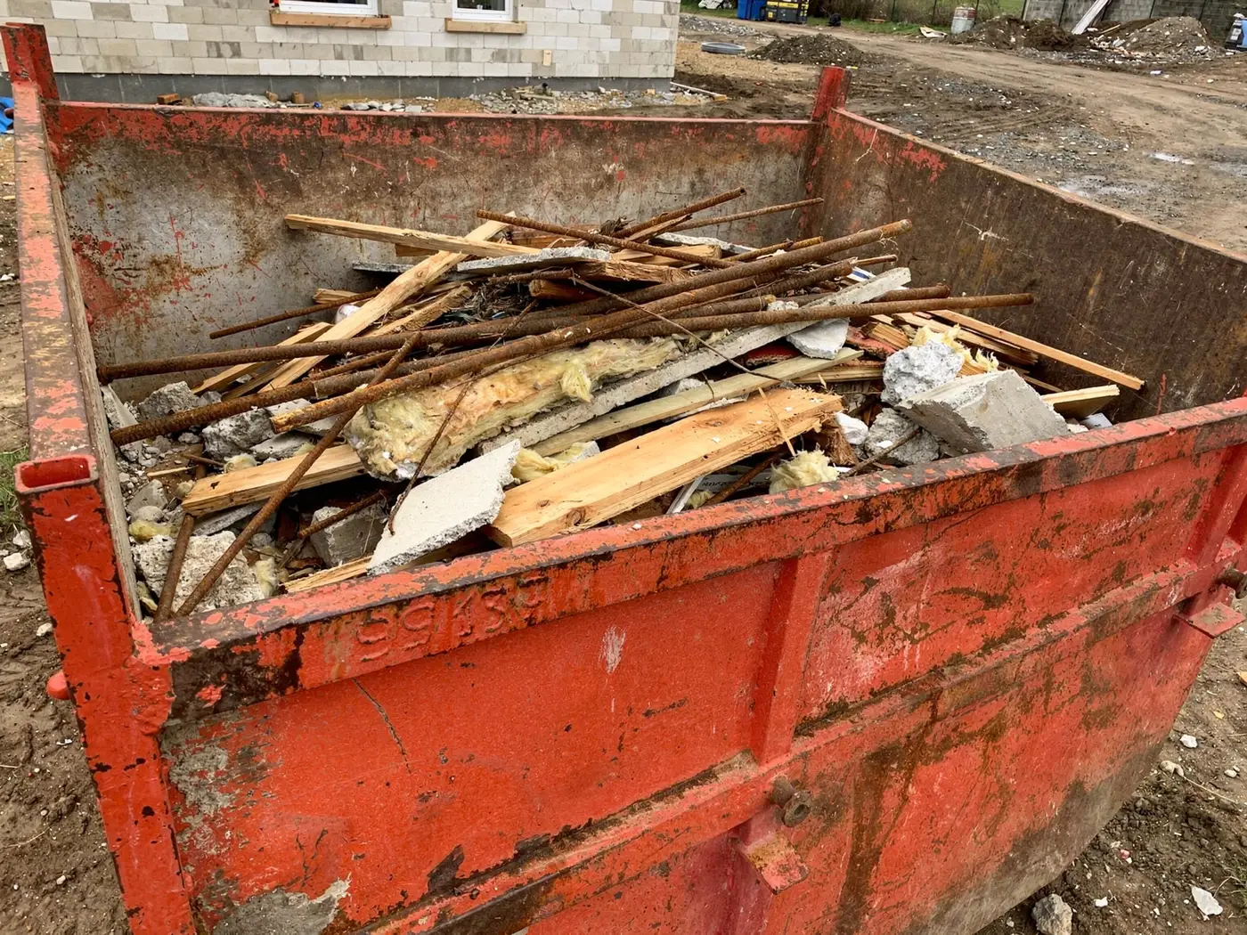 Benne de déchets de chantier avec bois, ferraille et béton