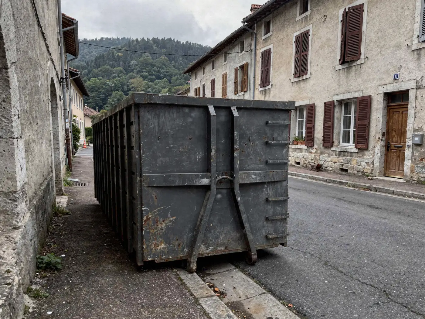 Benne posée le long d'un trottoir dans une rue de centre-ville près de Voiron
